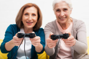 Two females senior citizens playing a video game with control pads