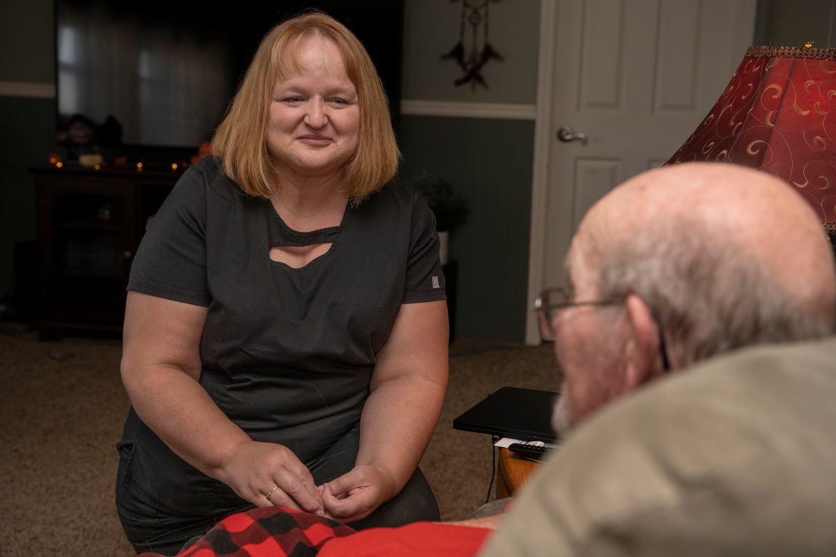 Firefly caregiver, Karilyn, talks with her client in his home.
